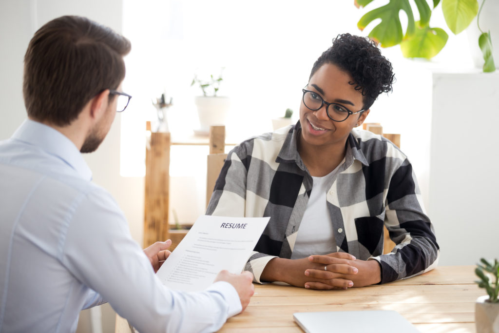 Run From a Job Offer, a job with red flags. Male employer holding resume talking with African American female job candidate at interview, black millennial girl recruitment process, speak with HR manager, businessman consider applicant cv